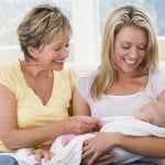 grandmother and mother in living room with baby smiling xs 150x150