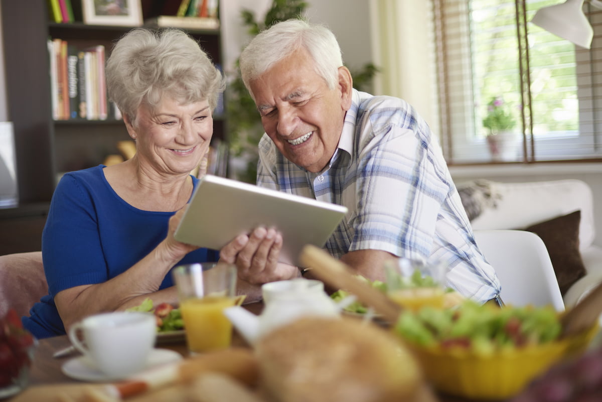 Modern couple of elder people using a touch pad